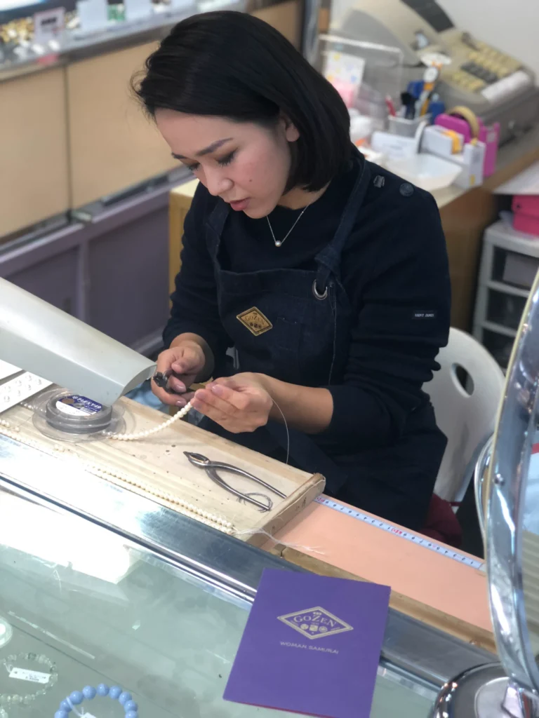 Gozen artisan applying Japanese gold leaf to pearls by hand — 13-generation heritage craft